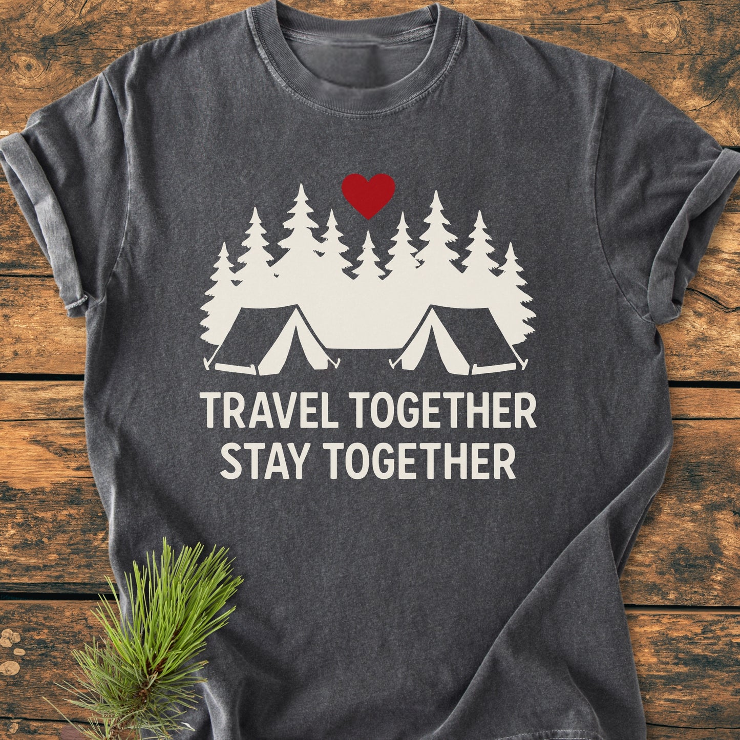 Travel Together Stay Together - Vintage Wash Tee features a campsite scene with tents and pine trees, highlighted by a red heart, on a dark-gray T-shirt laid flat with pine sprig accent.