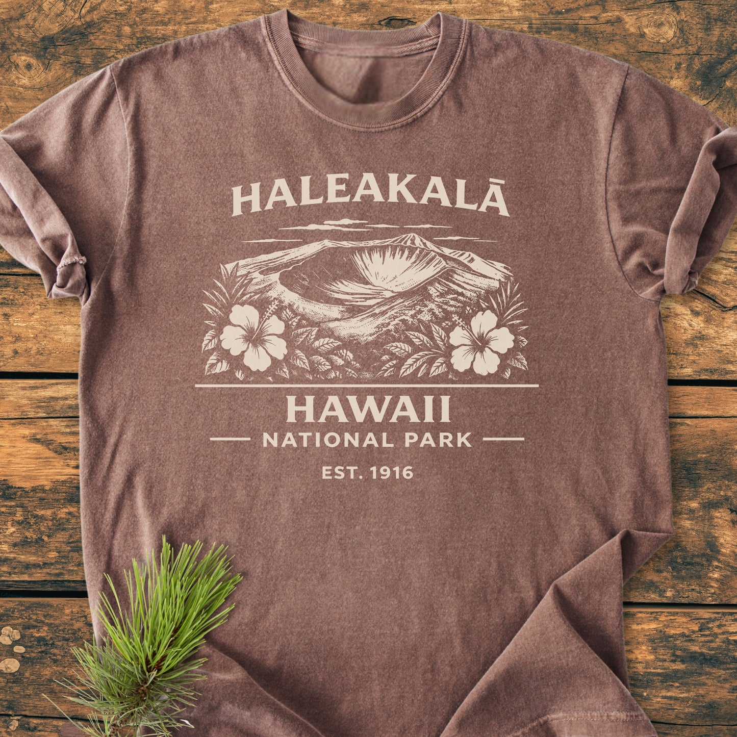 Haleakalā Hawaii National Park - Vintage Wash Tee featuring a cream graphic of a volcanic crater with hibiscus, laid flat on wood, showcasing its relaxed fit and durable double-needle stitching.