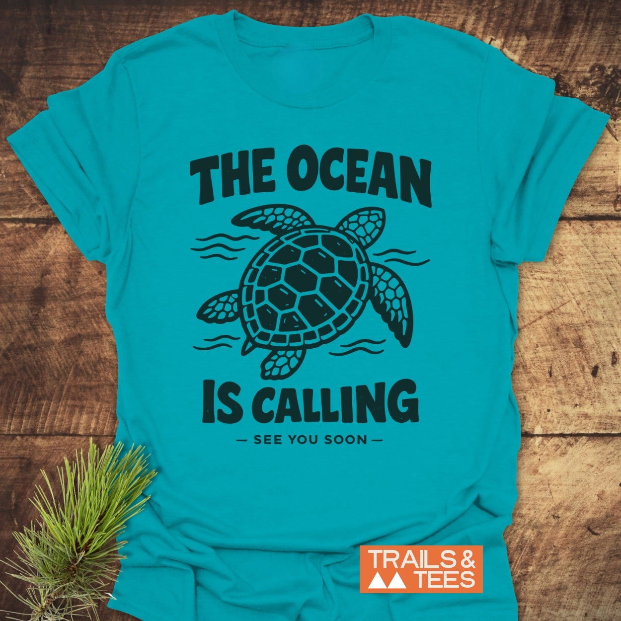 The Ocean Is Calling T-Shirt features a sea turtle design with wavy lines and slogan, crafted from soft cotton for comfort and durability, perfect for outdoor adventures.