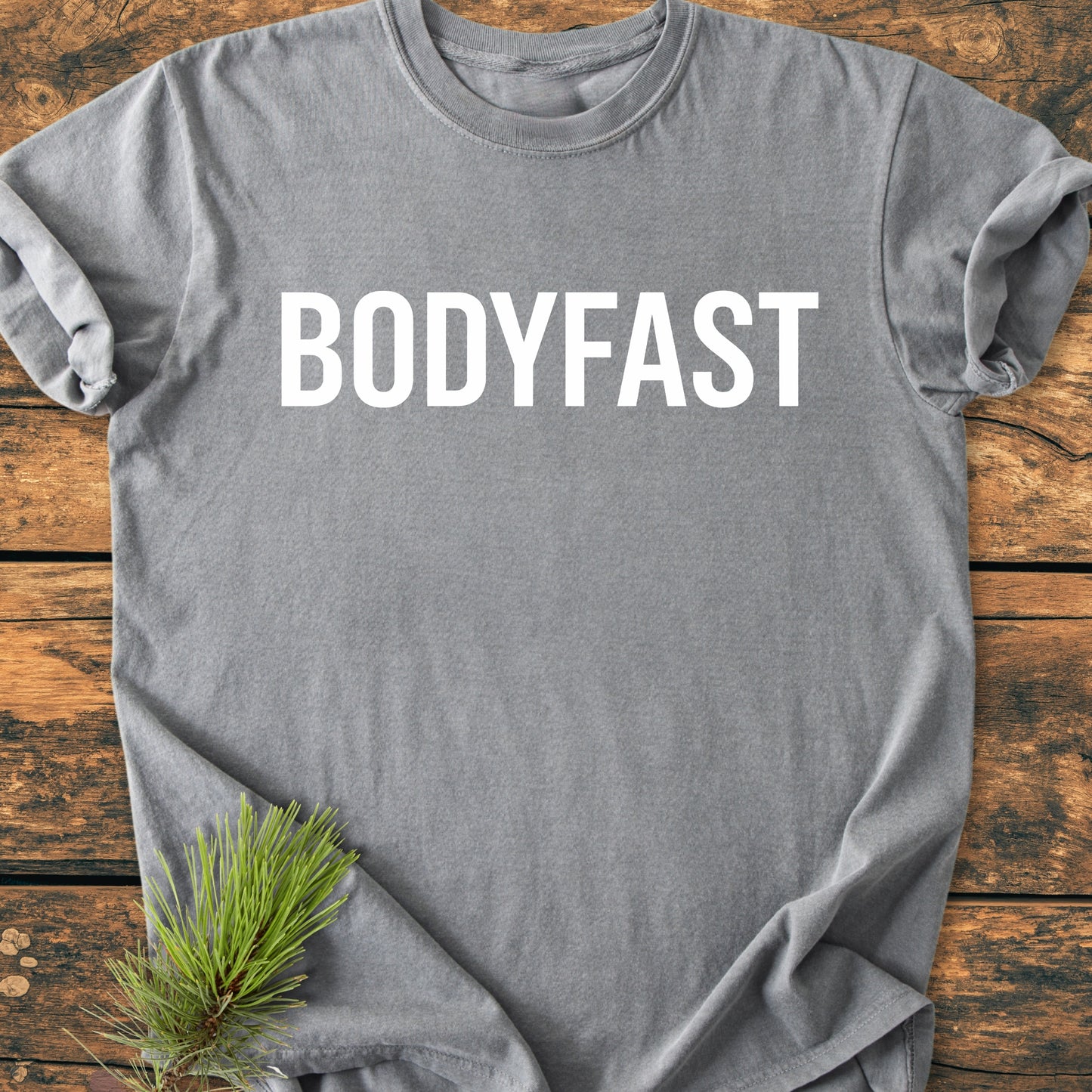 BODYFAST - Vintage Wash Tee: Soft gray T-shirt with bold white BODYFAST lettering, styled with a pine branch. A wearable reminder of a healthier, balanced lifestyle.