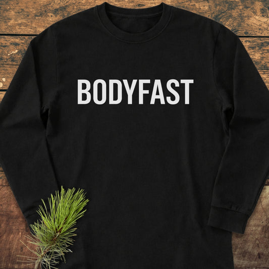 BODYFAST Long-Sleeve Tee in black, laid flat, features bold white lettering on chest. Made from 100% ring-spun cotton, this relaxed fit shirt exudes casual comfort and style.