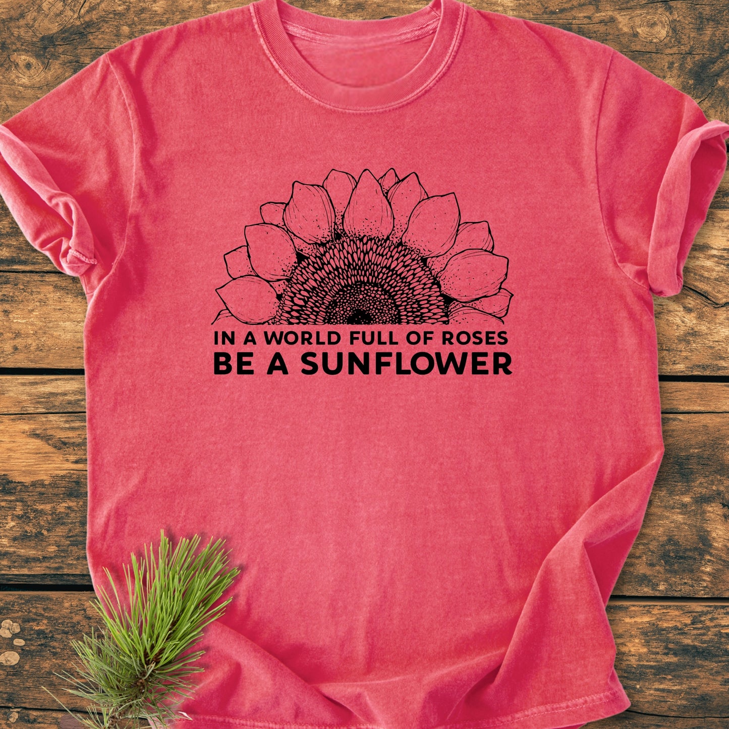 Be A Sunflower - Vintage Wash Tee featuring a half-sunflower line drawing and slogan, laid on rustic wood, with pine sprig accent; showcases Comfort Colors' soft-washed 100% ring-spun cotton design.