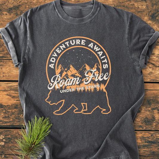 Roam Free Bear - Vintage Wash Tee features a bear silhouette with a mountain night sky scene, adorned with ADVENTURE AWAITS, Roam Free, and UNDER THE STARS, printed on charcoal-grey fabric.