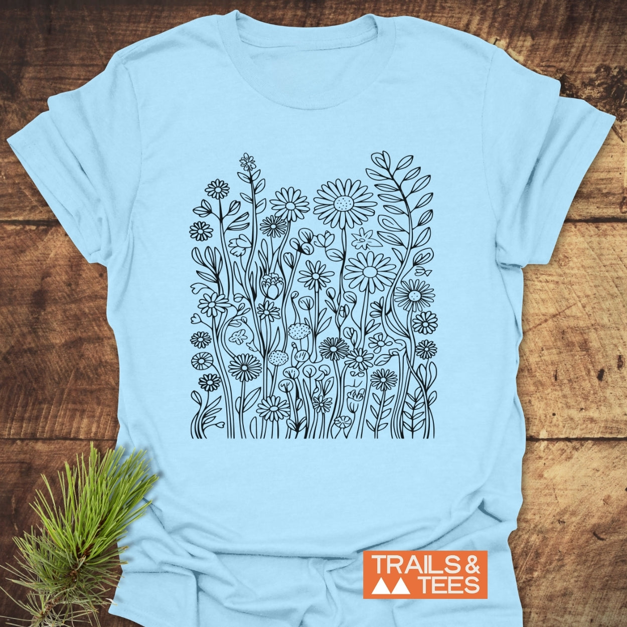 Wildflower Trail T-Shirt featuring a dense, hand-drawn black wildflower block design. Made from soft, lightweight cotton with a unisex fit, perfect for outdoor adventures and daily wear.