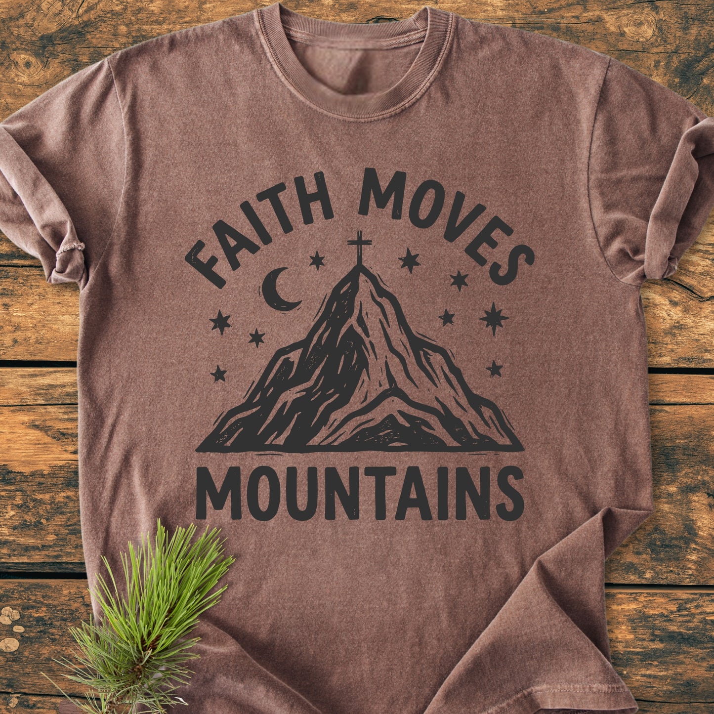 Faith Moves Mountains - Vintage Wash Tee laid flat, featuring “FAITH MOVES” above a mountain with a cross, stars, and moon. Soft, 100% cotton, relaxed fit. Pine sprig accentuates rustic style.