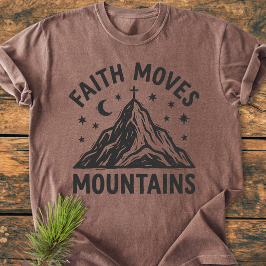 Faith Moves Mountains - Vintage Wash Tee laid flat, featuring “FAITH MOVES” above a mountain with a cross, stars, and moon. Soft, 100% cotton, relaxed fit. Pine sprig accentuates rustic style.