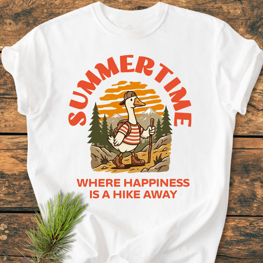 Summertime Hike - Vintage Wash Tee featuring a cartoon hiking goose in vibrant gear, surrounded by nature. Displayed on a wooden surface, highlighting its relaxed fit and cozy garment-dyed fabric.