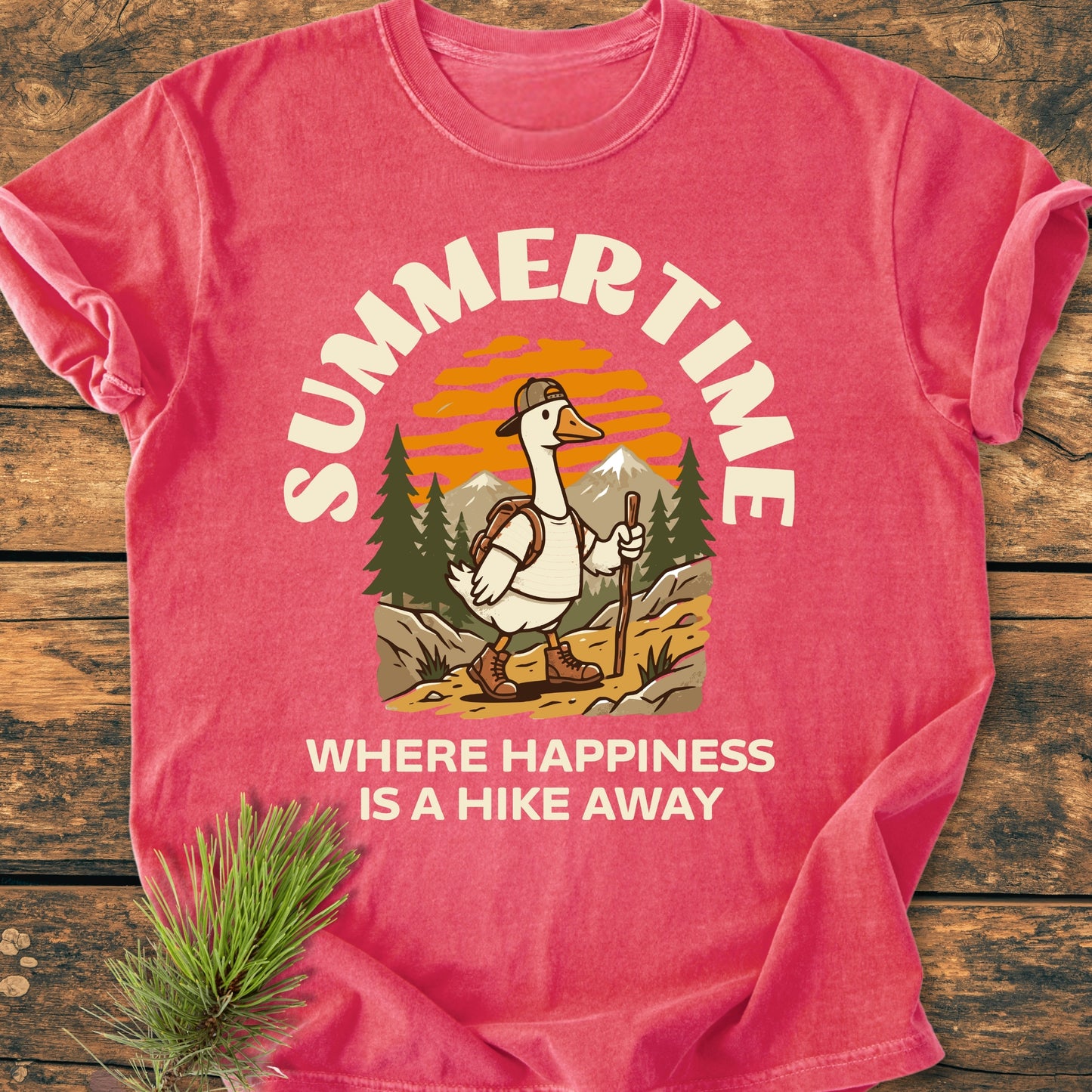 Summertime Hike - Vintage Wash Tee showcasing a hiking goose in boots and backpack, set against a mountain trail with pine trees and sunset, on a soft, relaxed-fit garment-dyed fabric.