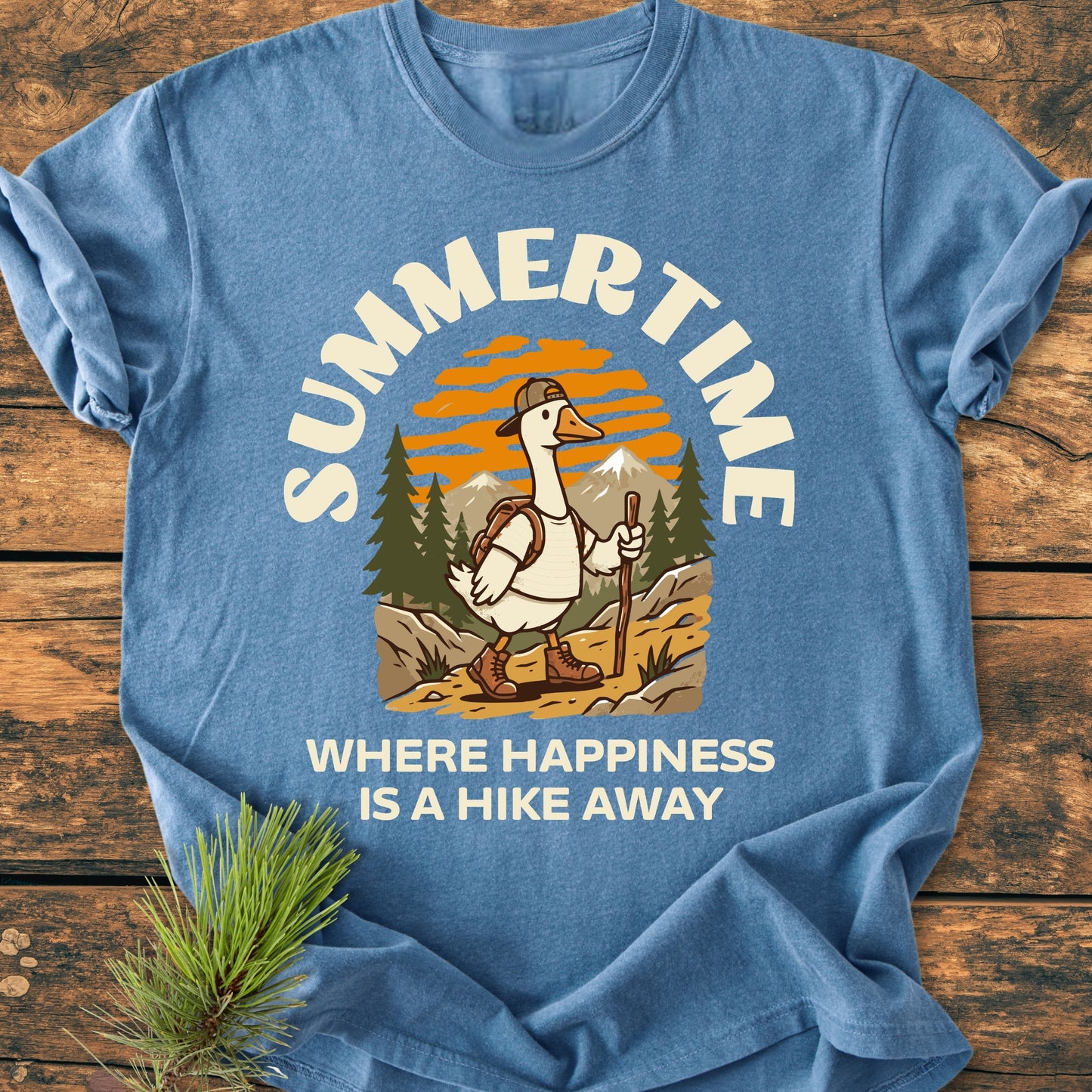 Summertime Hike - Vintage Wash Tee featuring a cartoon hiking goose in a mountain scene, Summertime above, and Where Happiness is a Hike Away below, on soft, garment-dyed fabric.