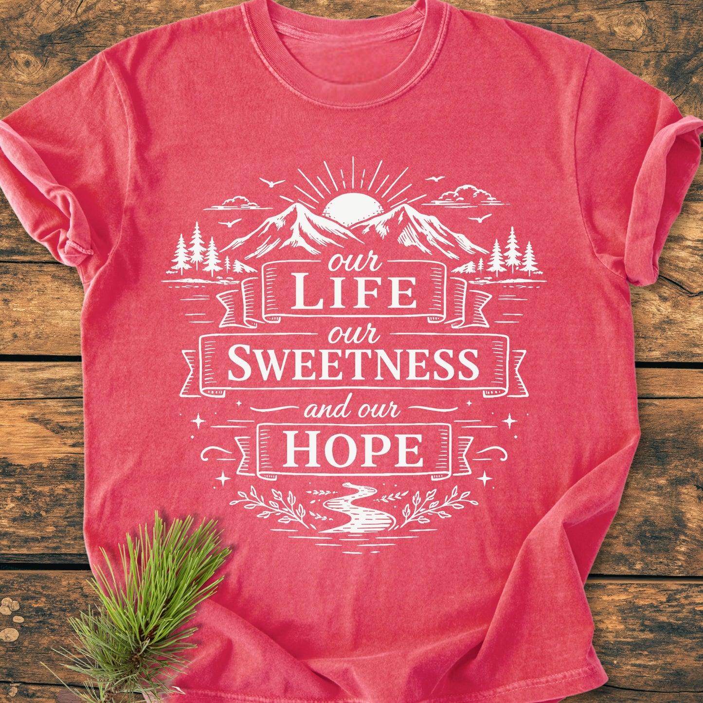 Our Life, Our Sweetness, Our Hope - Vintage Wash Tee features a serene outdoor illustration with mountains and sun, on a soft, relaxed-fit, garment-dyed T-shirt, accented by a pine sprig.