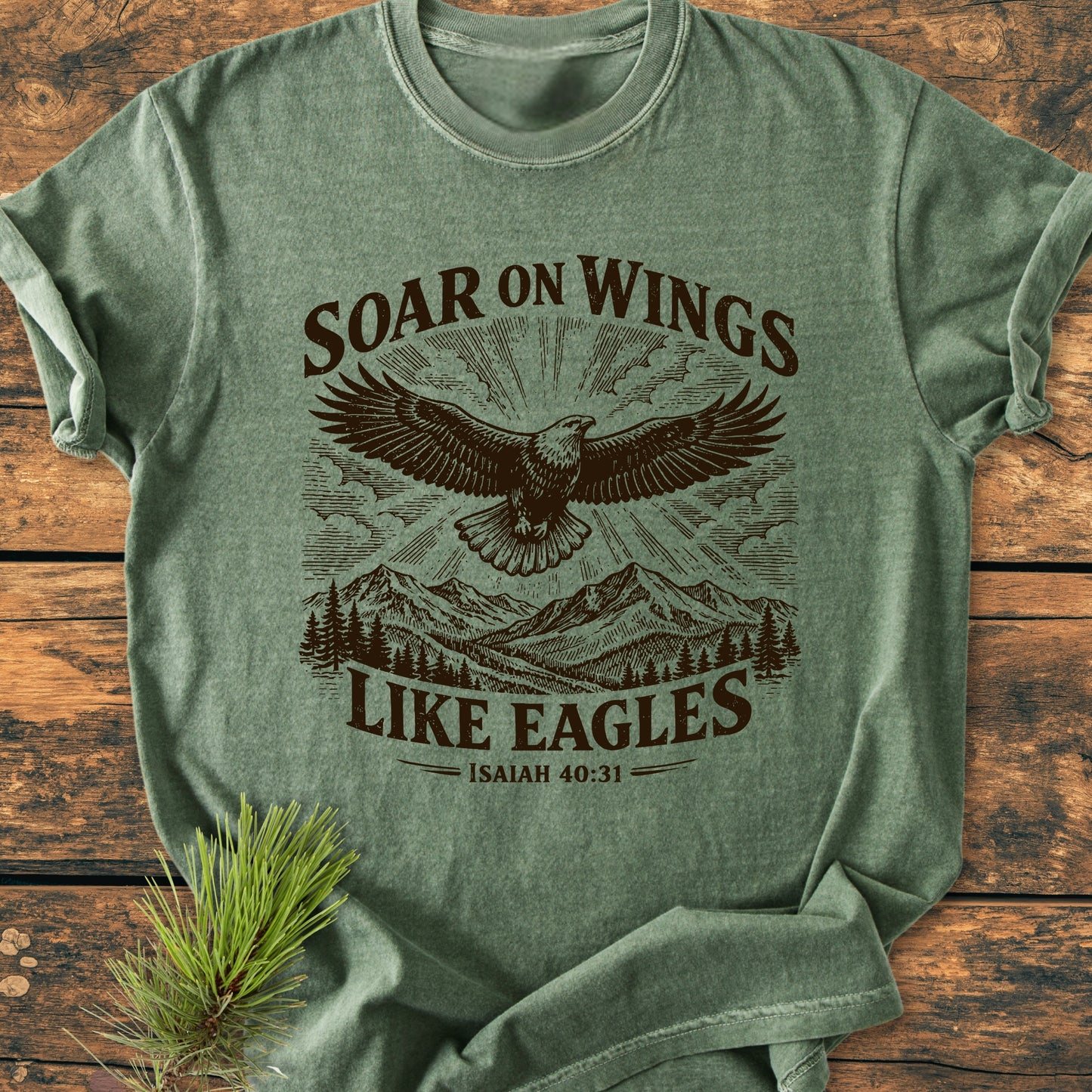 Soar On Wings Like Eagles Isaiah 40:31 - Vintage Wash Tee features a stylized eagle print over mountains and trees, emphasizing comfort with its relaxed fit and durable, soft-washed cotton fabric.