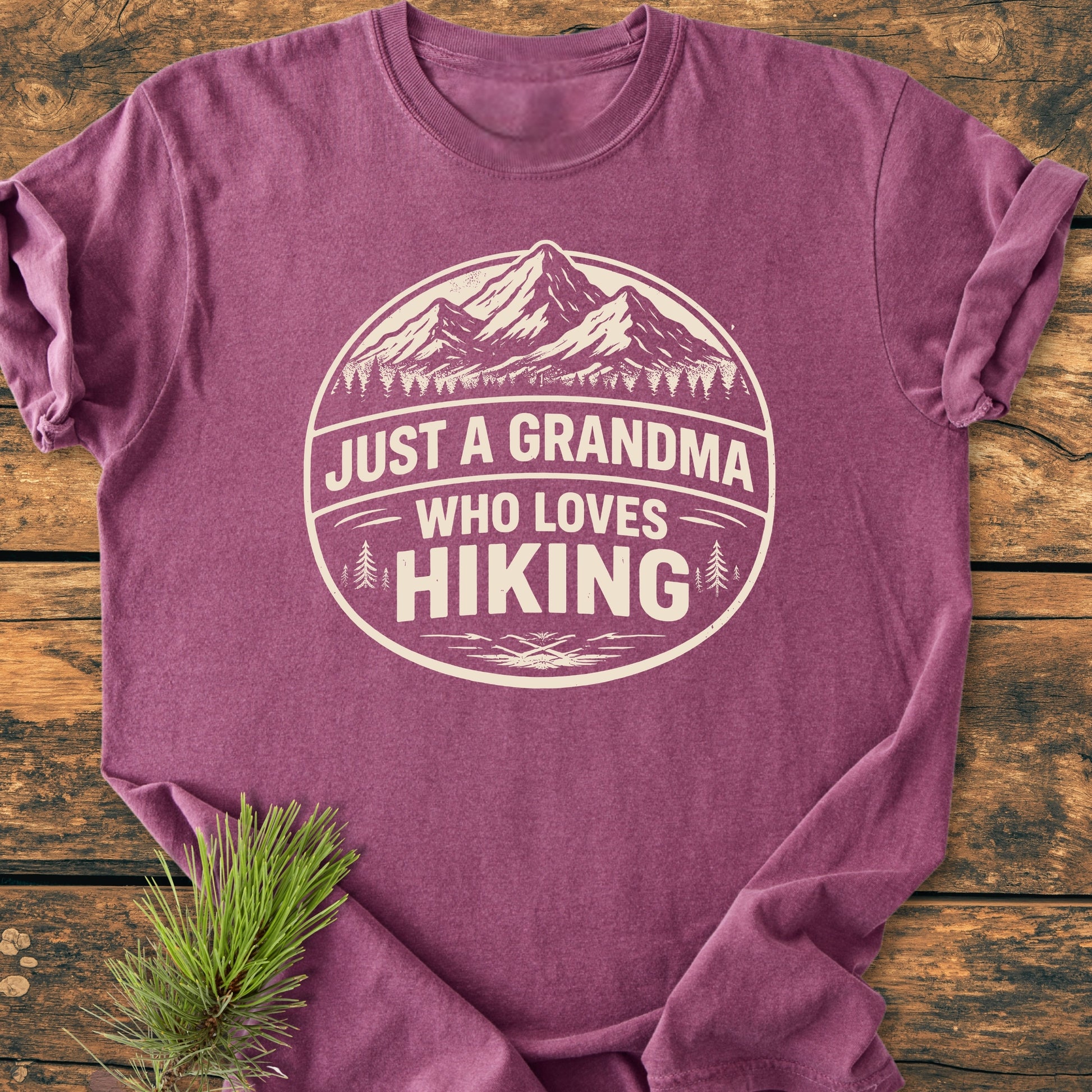 Just A Grandma Who Loves Hiking - Vintage Wash Tee features a mountain and pine tree badge on soft, heathered fabric, ideal for comfort and durability with its relaxed fit and ring-spun cotton.