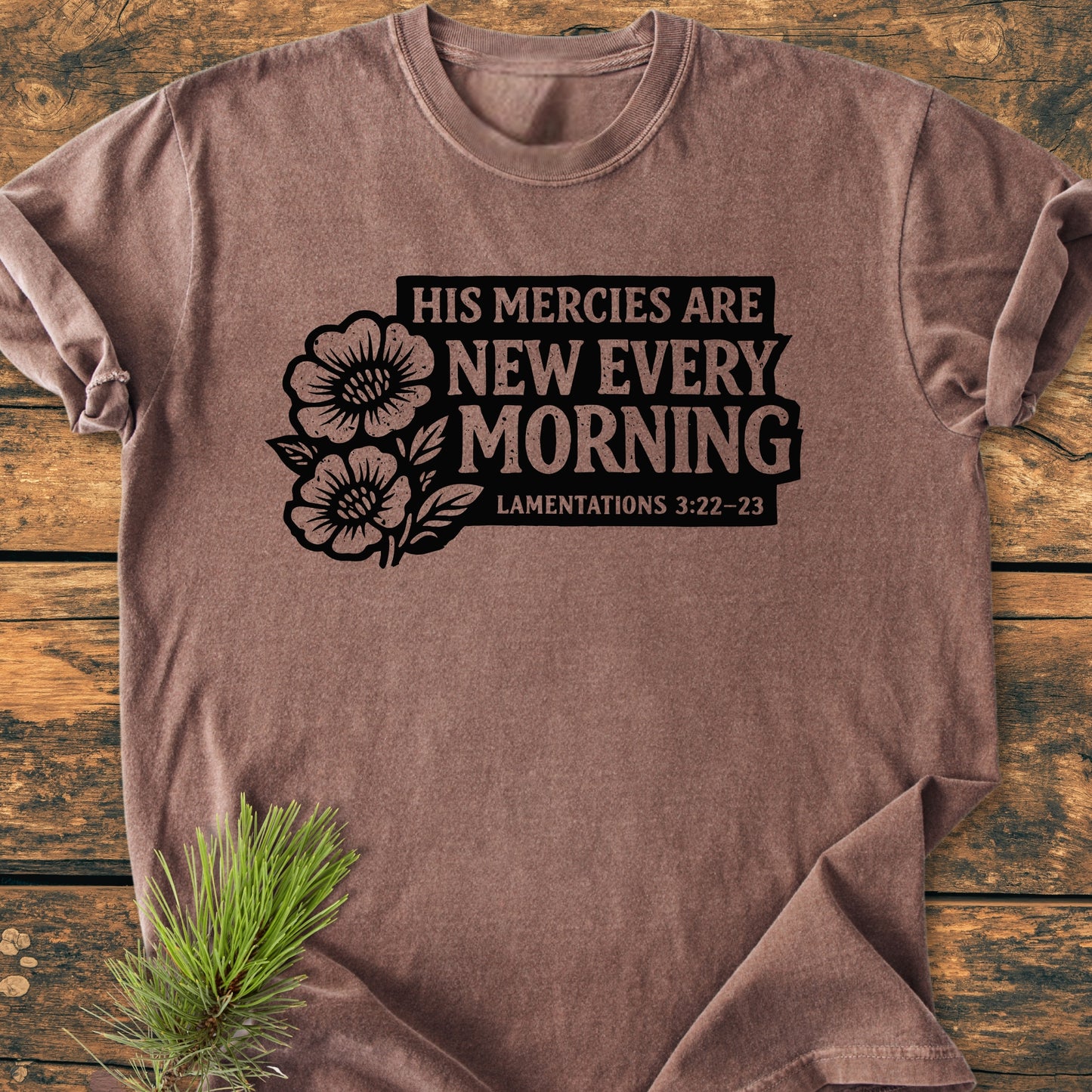New Every Morning Lamentations 3:22-23 - Vintage Wash Tee, heather-brown with bold black text and floral illustration, laid flat on wood. Comfortable, relaxed fit, garment-dyed for softness.