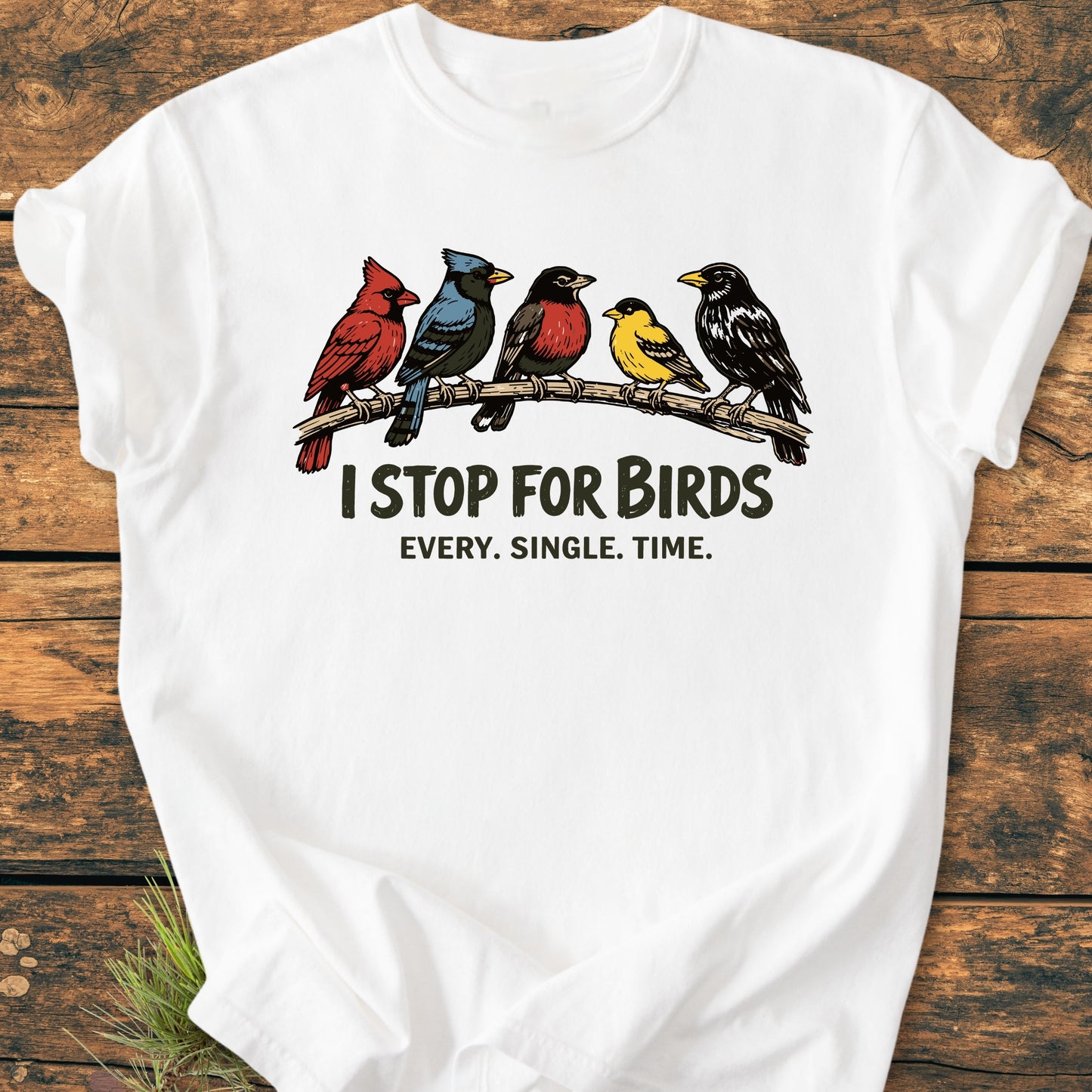 I Stop For Birds - Vintage Wash Tee featuring five songbirds and slogan on a white T-shirt, laid on a wooden surface. Made from 100% ring-spun cotton, offering a relaxed fit.