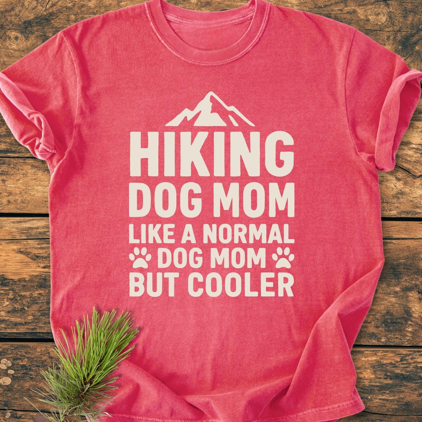 Red-coral Hiking Dog Mom - Vintage Wash Tee on wood surface, features bold white text and mountain icon. Made of soft, ring-spun cotton with a relaxed fit and durable stitching.