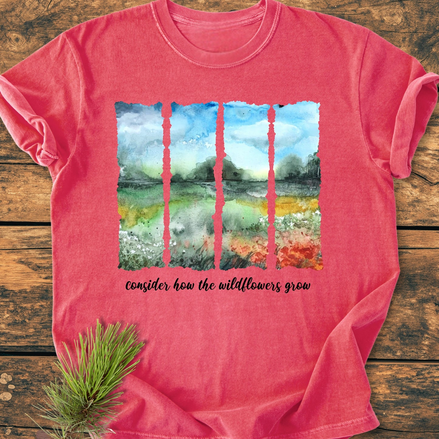 The Mountains Are Calling - Vintage Heavyweight Tee features a watercolor landscape and cursive slogan on a coral-red T-shirt, laid on wood, highlighting its relaxed fit and garment-dyed softness.