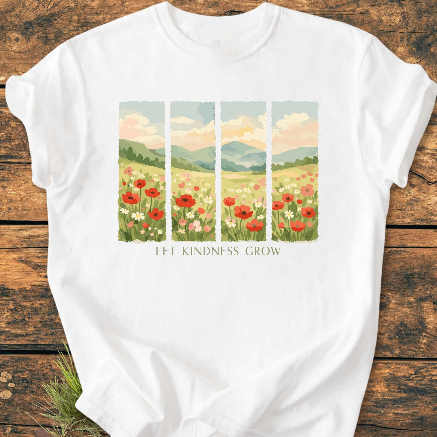 Let Kindness Grow - Vintage Heavyweight Tee features a painterly meadow design with red poppies and daisies. Laid on a wooden surface, showcasing its relaxed fit and durable, soft-washed 100% ring-spun cotton fabric.