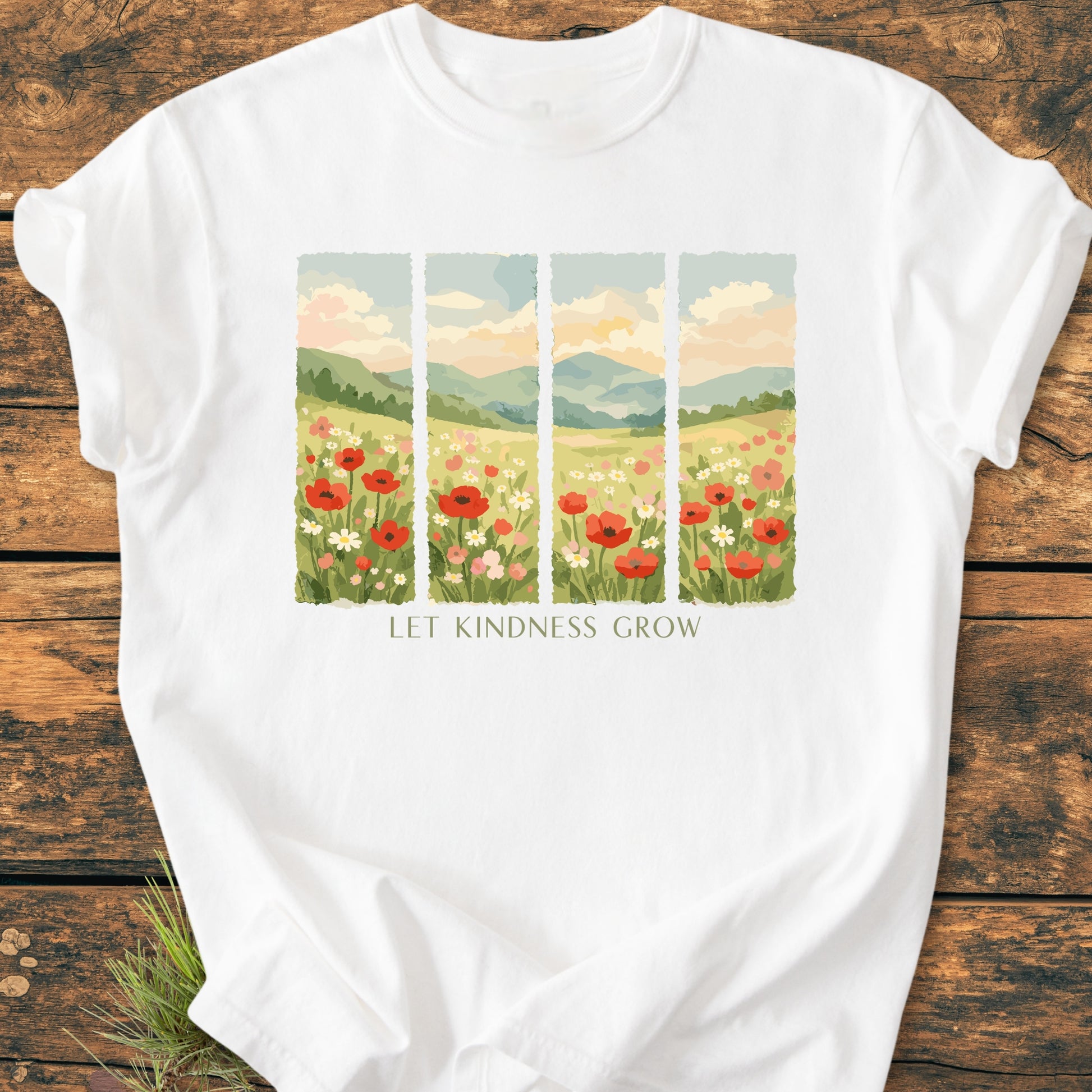Let Kindness Grow - Vintage Heavyweight Tee features a painterly meadow design with red poppies and daisies. Laid on a wooden surface, showcasing its relaxed fit and durable, soft-washed 100% ring-spun cotton fabric.