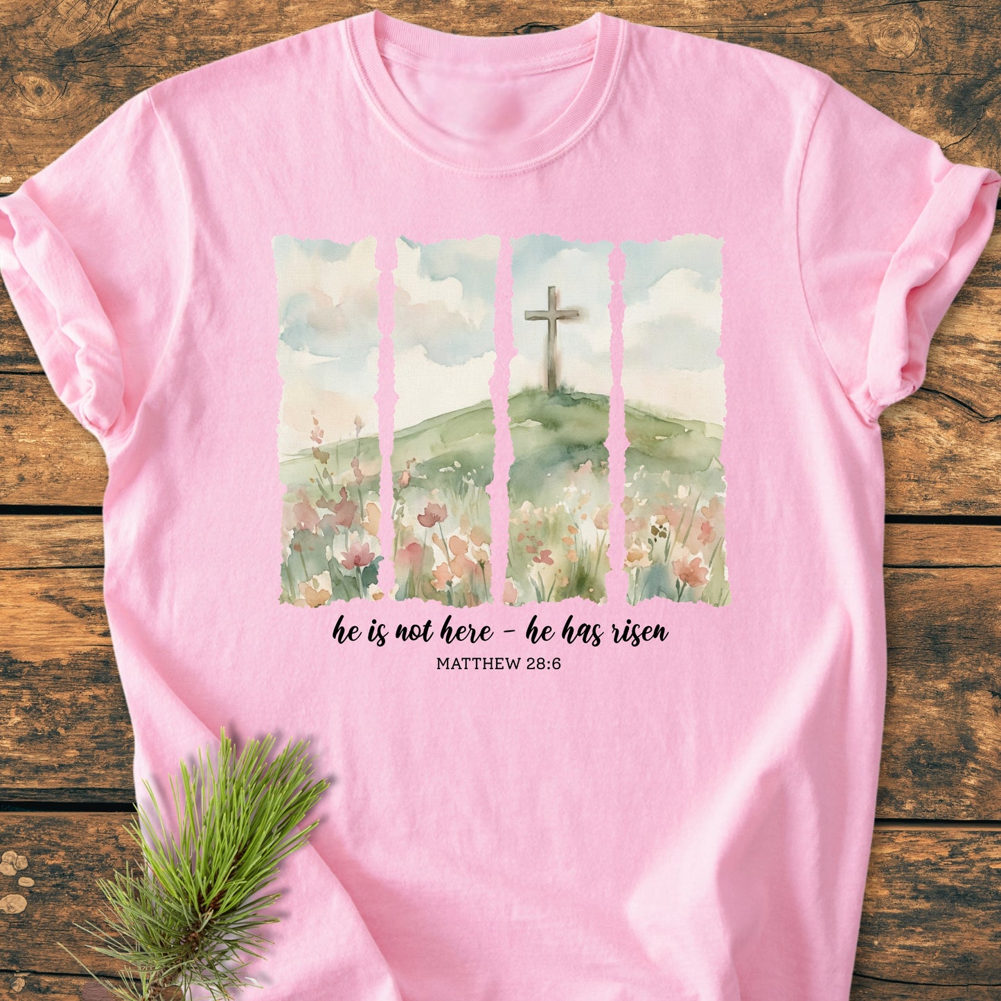 He Is Not Here. He Has Risen - Vintage Heavyweight Tee features watercolor panels of a cross on a hill with wildflowers, scriptural text, on a soft pink, durable, garment-dyed cotton fabric.