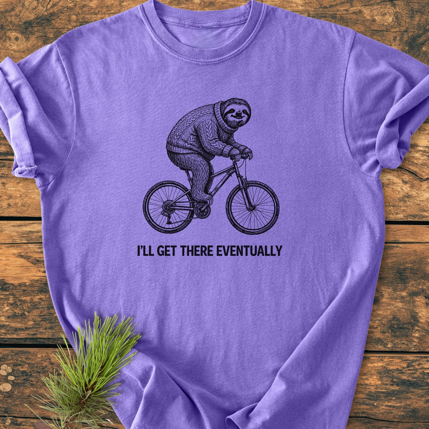 I'll Get There Eventually - Vintage Wash Tee with a sloth in a sweater on a bicycle, captioned humorously, styled with a pine sprig, showcasing its relaxed fit and durability.