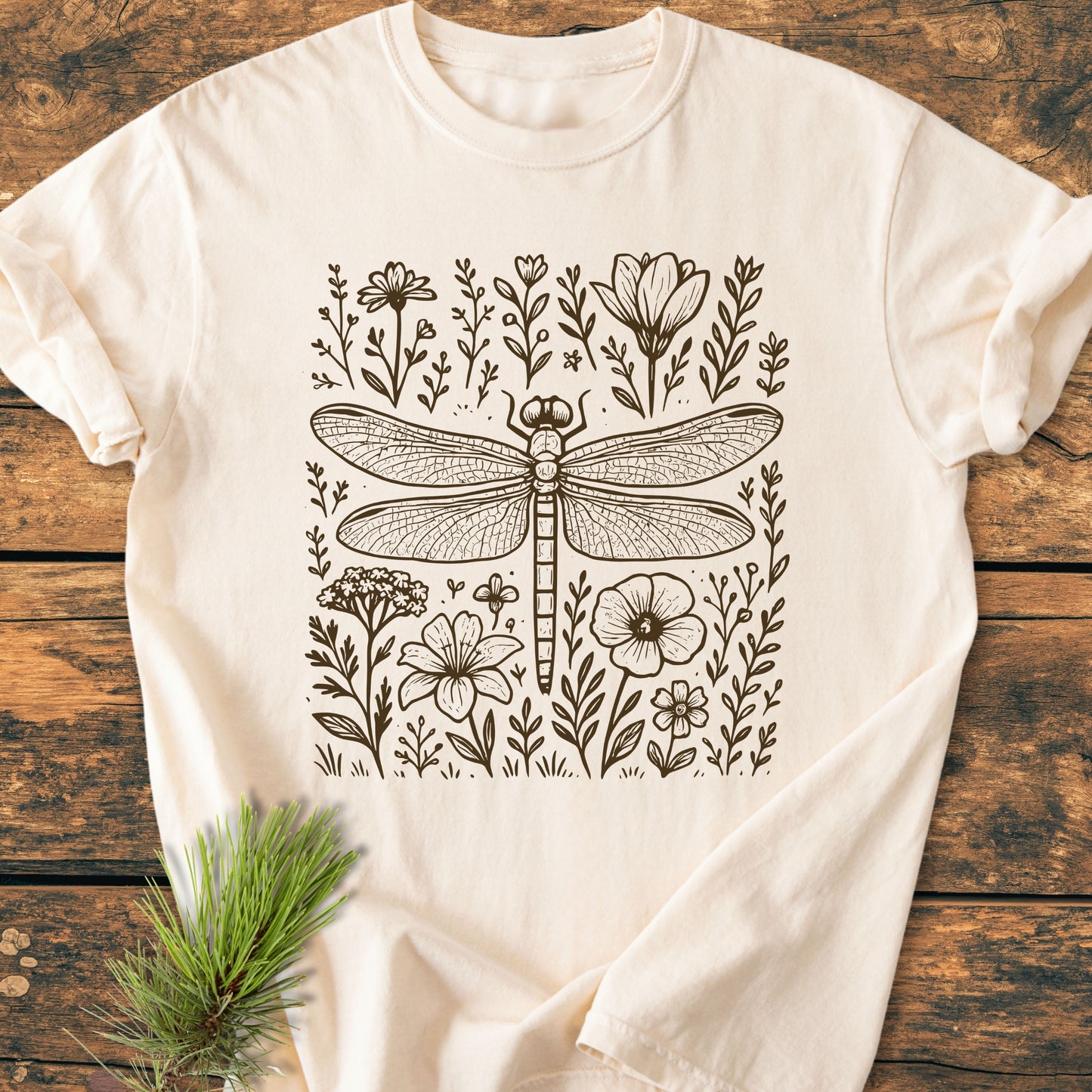 Dragonfly - Vintage Heavyweight Tee with a dragonfly and wildflower line-drawing print, displayed on a wooden surface, showcasing its relaxed fit and soft-washed, garment-dyed fabric for everyday comfort.
