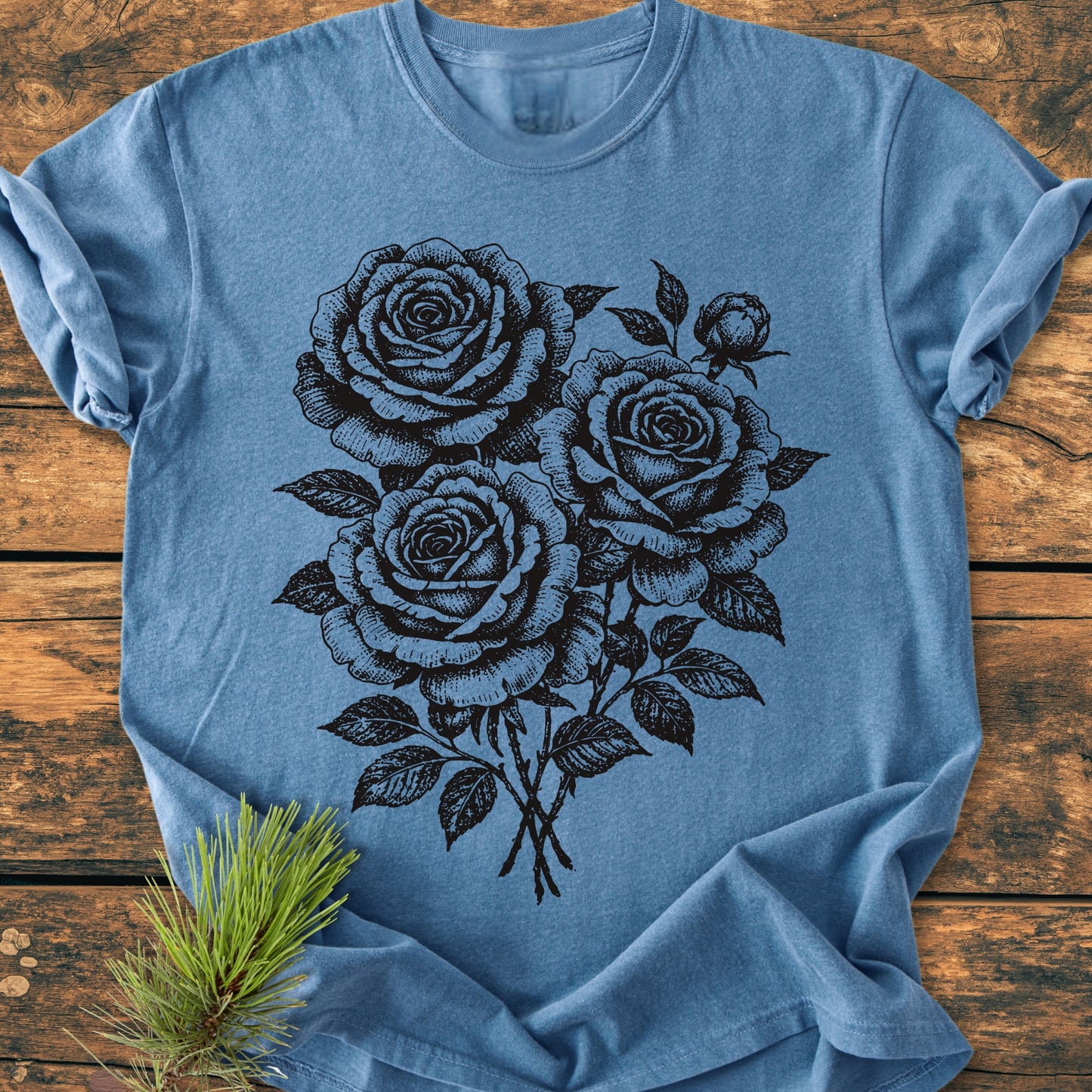 Rose Bouquet - Vintage Heavyweight Tee on wood, featuring a black line-drawing of three roses and a bud. The soft blue, relaxed-fit tee emphasizes comfort with its garment-dyed, ring-spun cotton fabric.