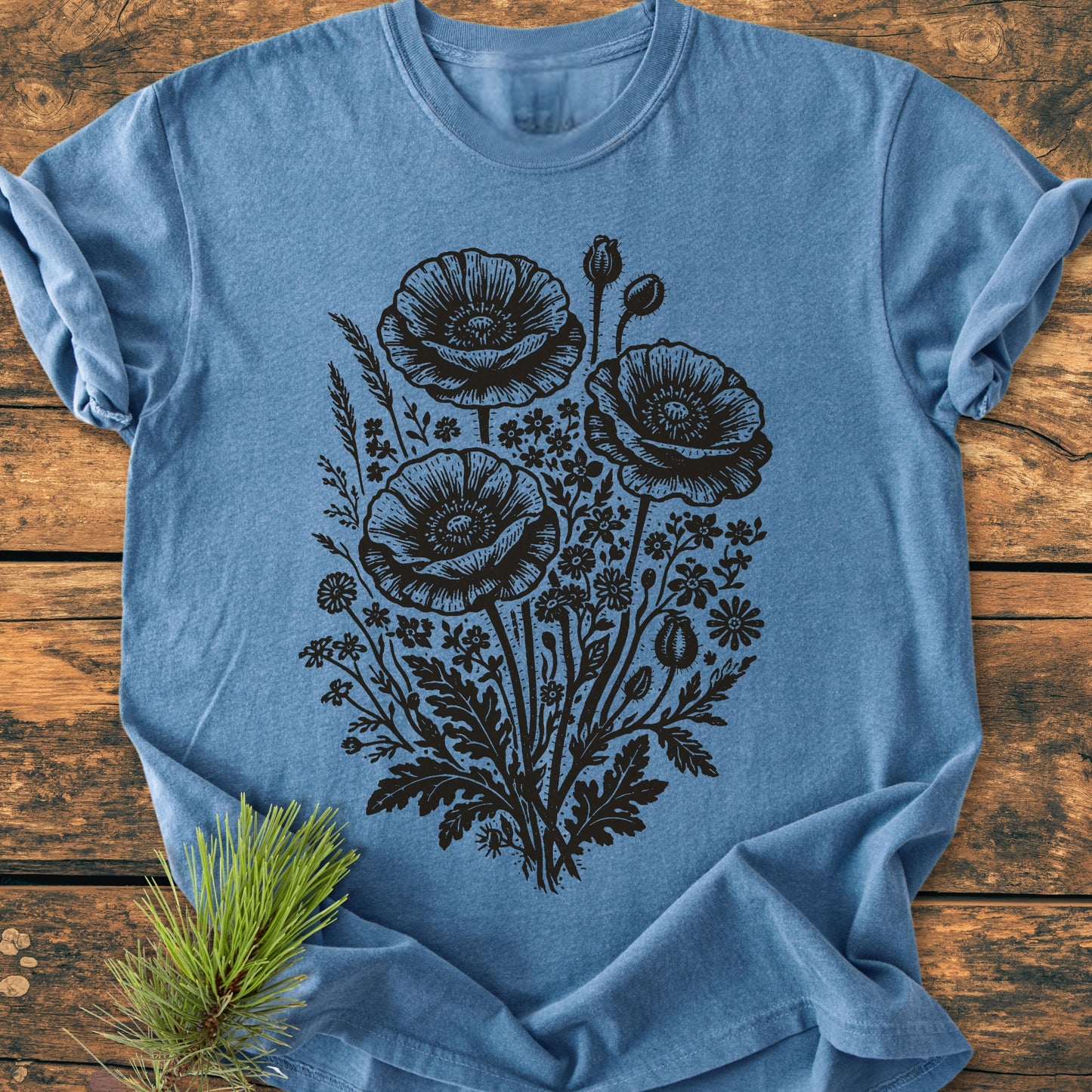 Wildflower Bouquet - Vintage Heavyweight Tee, featuring a bold black floral graphic with poppy-style blossoms, displayed on a wooden background with a pine sprig for added styling.