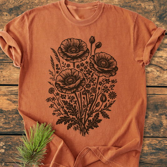Wildflower Bouquet - Vintage Heavyweight Tee featuring black line-art poppy flowers with wildflowers on rust-orange fabric, laid on wood. Made from soft 100% ring-spun cotton, ensuring comfort and durability.