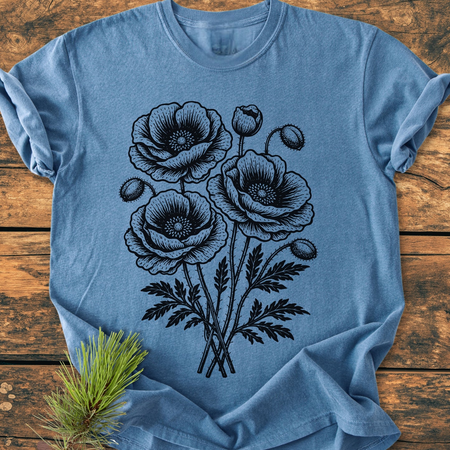 Poppy Bouquet - Vintage Heavyweight Tee features a black line-drawing of poppy blooms and buds. Laid on wood, it showcases a soft, relaxed fit ideal for everyday wear.