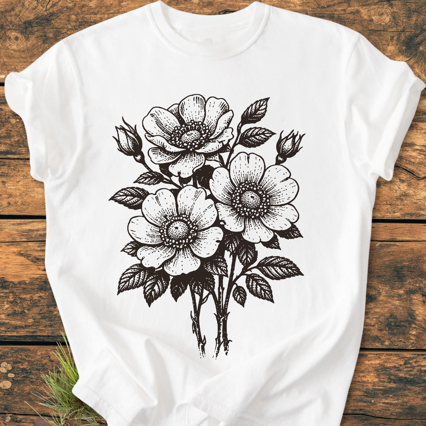 Wild Rose Bouquet - Vintage Heavyweight Tee displayed flat, featuring a black-ink illustration of three large, open-petaled flowers in a hand-drawn, woodcut style on a white background.