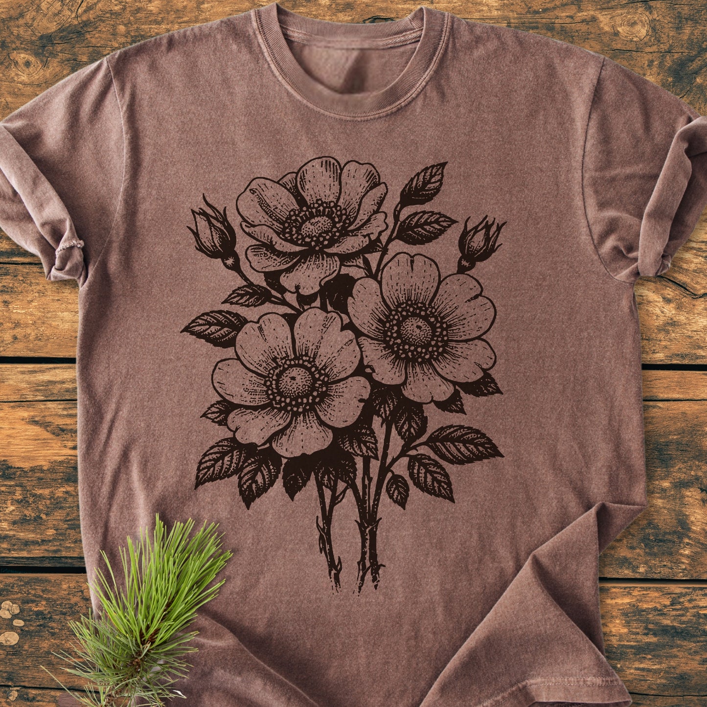 Wild Rose Bouquet - Vintage Heavyweight Tee, featuring a black floral illustration, lies flat on a wooden surface. Crafted from soft, pre-shrunk cotton, it offers a relaxed fit and durable double-needle stitching.
