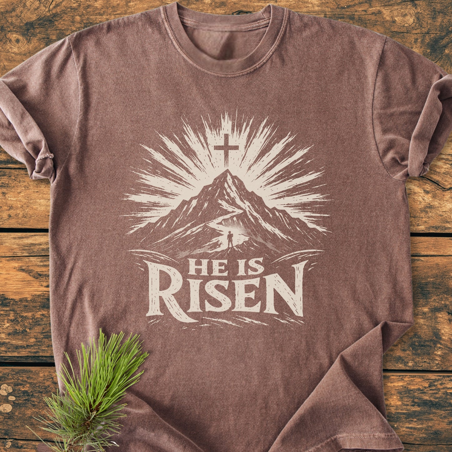 He Is Risen - Vintage Wash Tee features a mountain and rising-sun motif with a cross. Made from soft, pre-shrunk 100% ring-spun cotton, it offers a relaxed fit and durable construction.
