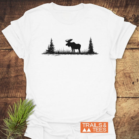 Lone Moose T-Shirt featuring a black moose silhouette with trees on soft, ring-spun cotton, laid on wood. Includes an orange TRAILS & TEES logo, emphasizing outdoor adventure and comfort.