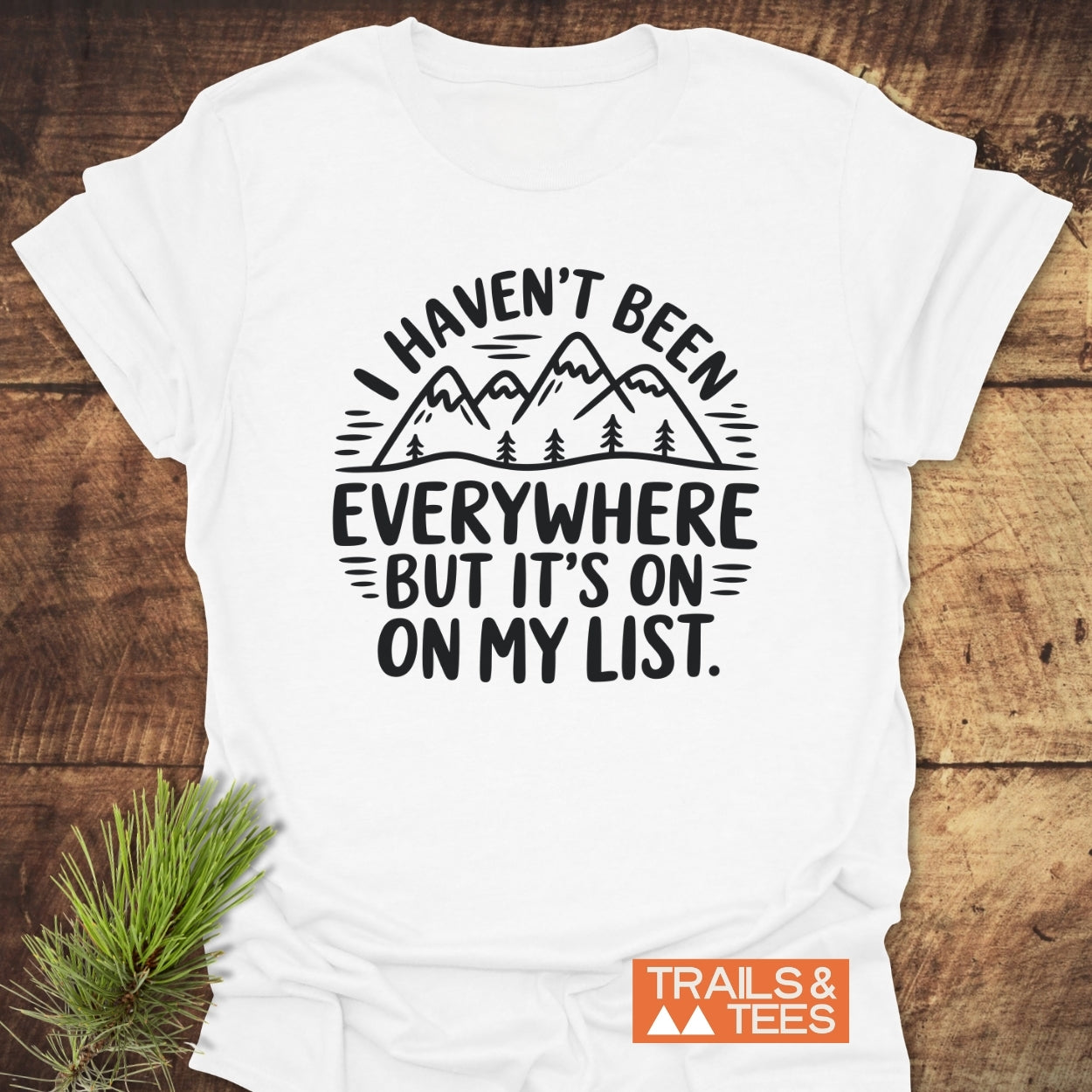 On My List T-Shirt features a black graphic of mountains and trees with the phrase I HAVEN’T BEEN EVERYWHERE BUT IT’S ON MY LIST on soft, ring-spun cotton, ideal for outdoor enthusiasts.