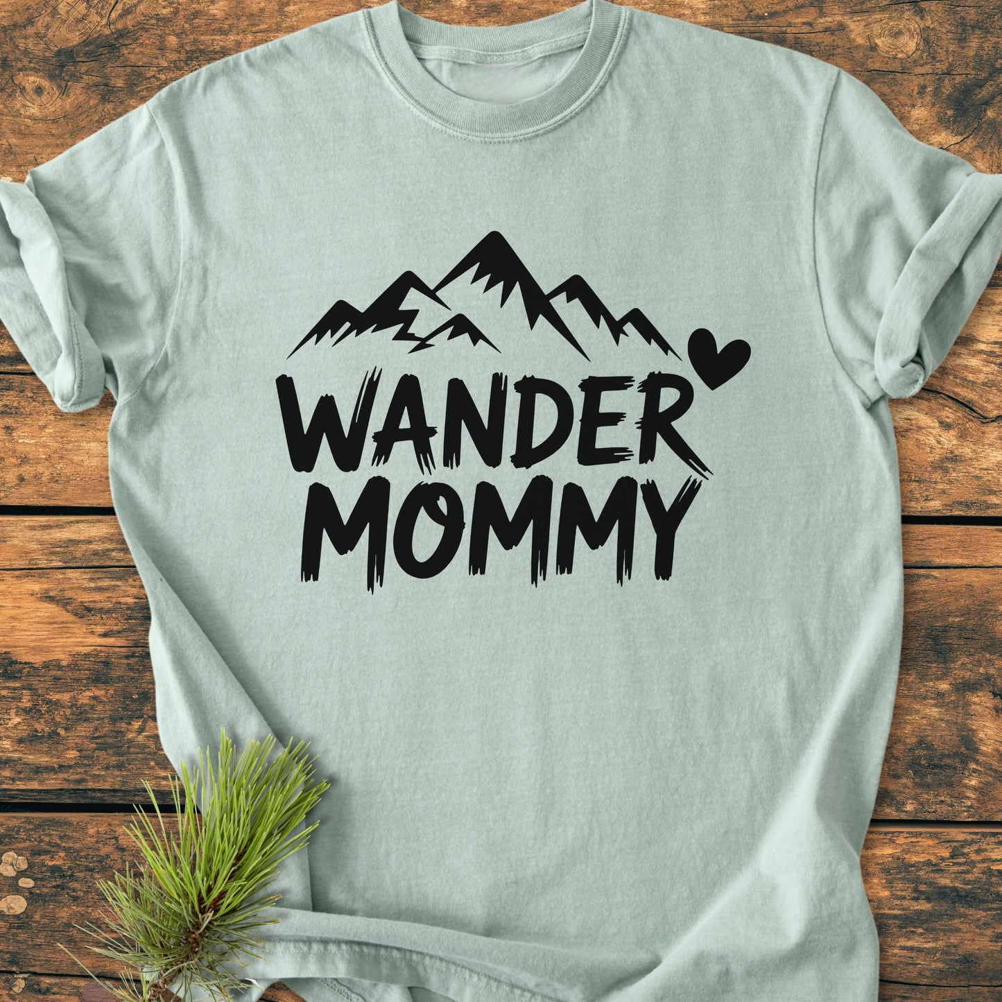 Wander Mommy - Vintage Heavyweight Tee: Light mint-green T-shirt with 'WANDER MOMMY' and mountain silhouette, styled with a pine sprig. Ideal for daily wear, combining comfort and durability.