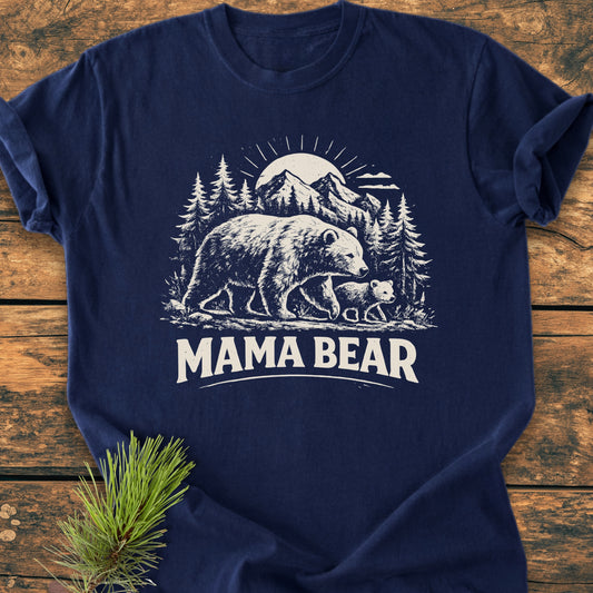 Mama Bear - Vintage Heavyweight Tee featuring a white graphic of a mother bear and cub against a mountain scene, laid on wood with a pine sprig, highlighting its relaxed fit and soft-washed cotton texture.