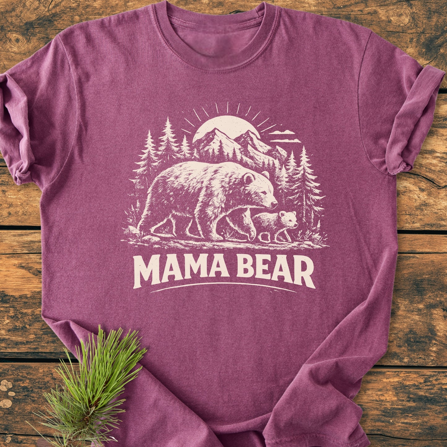 Mama Bear - Vintage Heavyweight Tee featuring a mother bear and cub illustration with MAMA BEAR text. Laid on a wooden surface, highlighting its relaxed fit and durable, soft-washed cotton fabric.