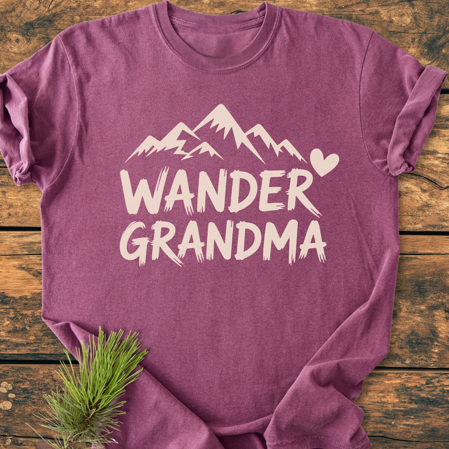 Wander Grandma - Vintage Heavyweight Tee featuring a mountain print and text, laid flat on wood with a pine branch; crafted from garment-dyed, ring-spun cotton for a cozy, relaxed fit.