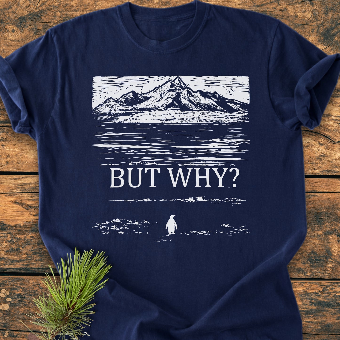 The But Why - Vintage Heavyweight Tee showcases a mountain design with “BUT WHY?” text and a penguin silhouette, displayed on a navy-blue T-shirt, emphasizing comfort and durability.
