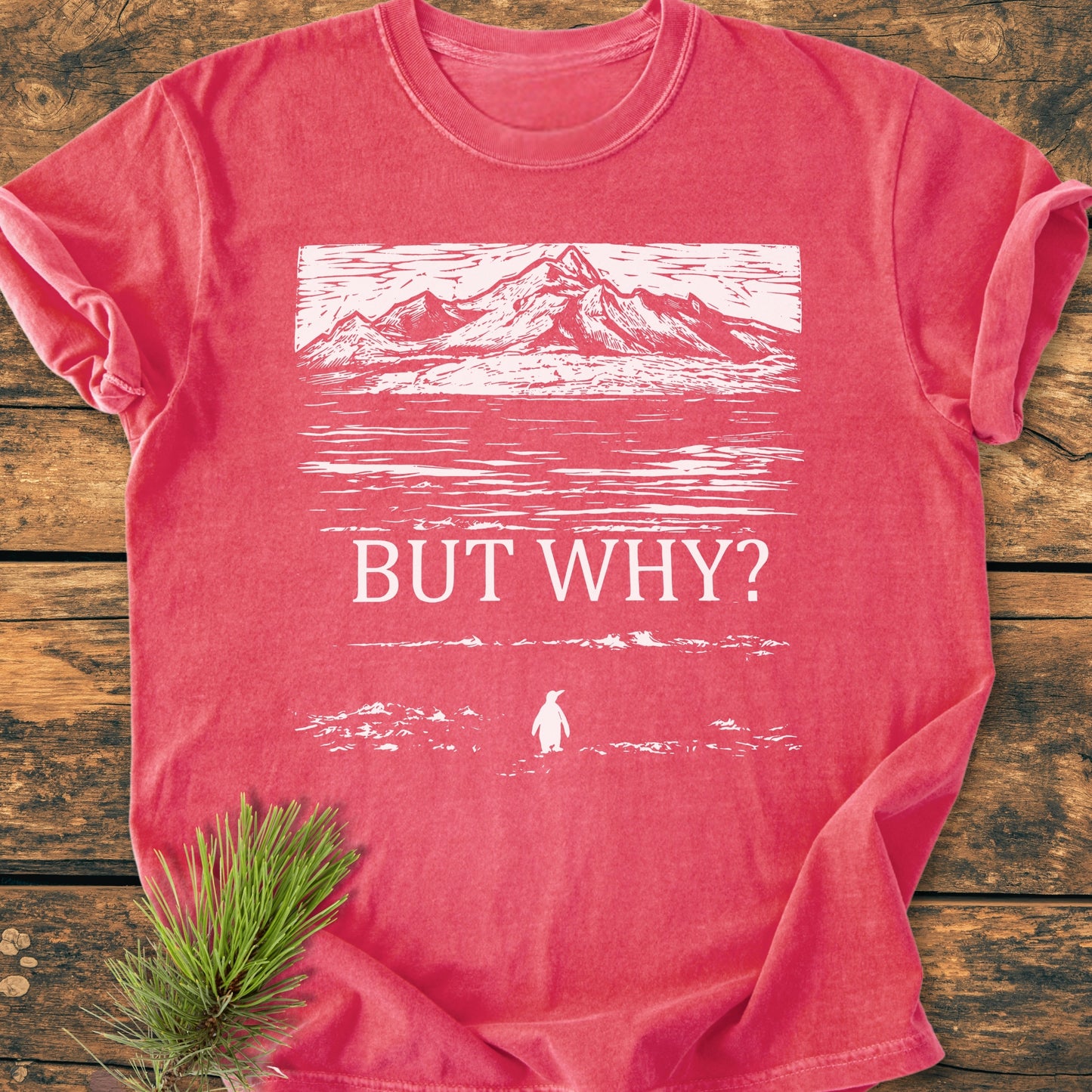 But Why - Vintage Heavyweight Tee featuring distant mountains, water reflection, and penguin silhouette, laid on wooden surface with pine branch, showcasing Comfort Colors' soft-washed, garment-dyed fabric and relaxed fit.