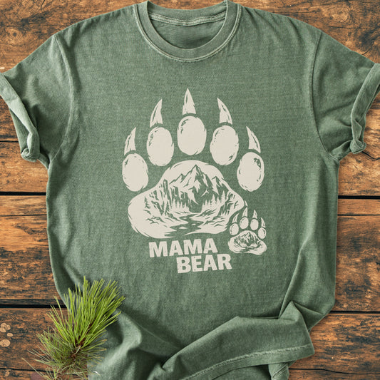 Mama Bear - Vintage Heavyweight Tee showcases a forest-green T-shirt with a stylized bear paw print featuring a mountain scene. MAMA BEAR text appears below, exuding a cozy, relaxed fit.