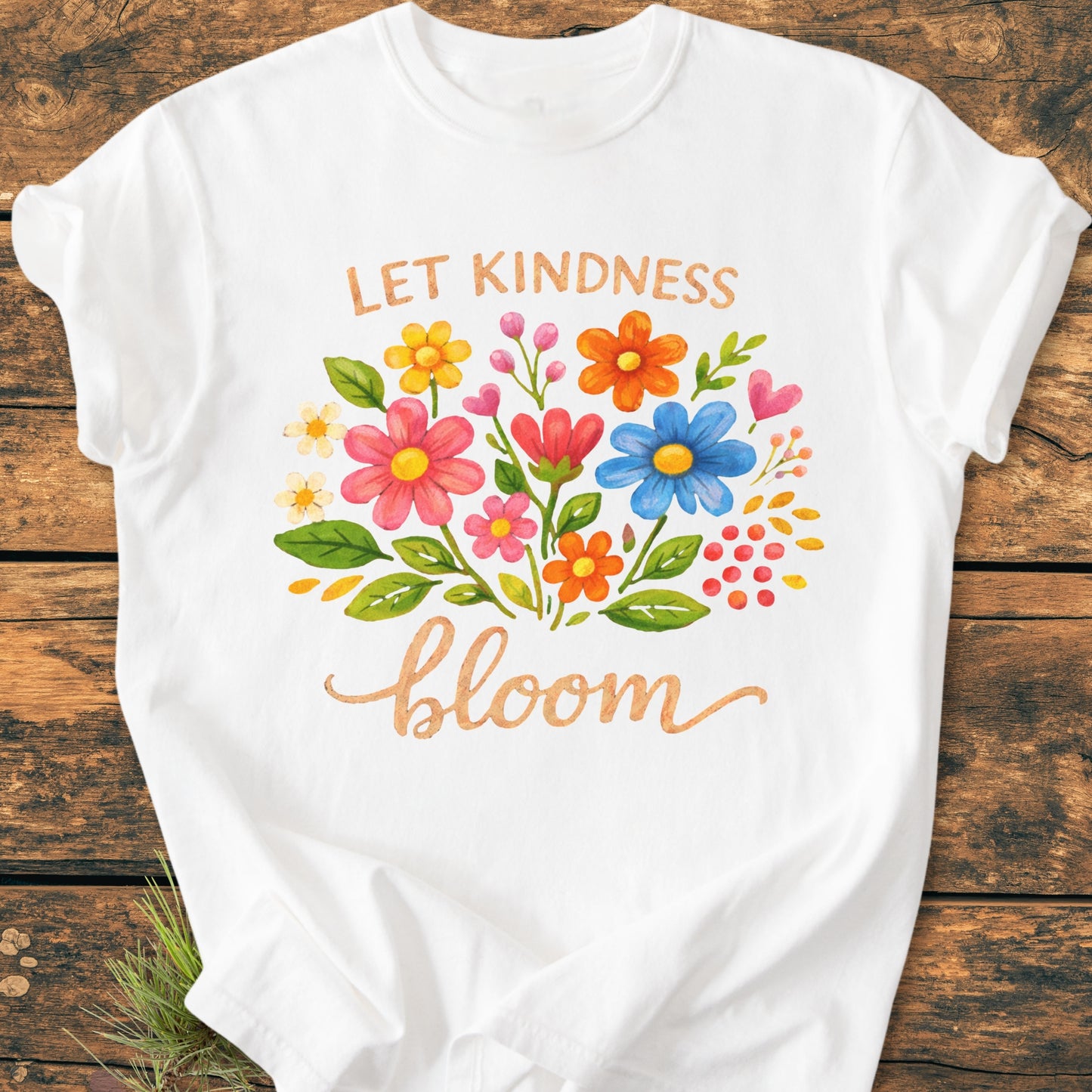 Let Kindness Bloom - Vintage Wash Tee features a hand-painted floral bouquet with 'LET KINDNESS bloom' text, displayed on a soft, garment-dyed white T-shirt on a rustic surface.