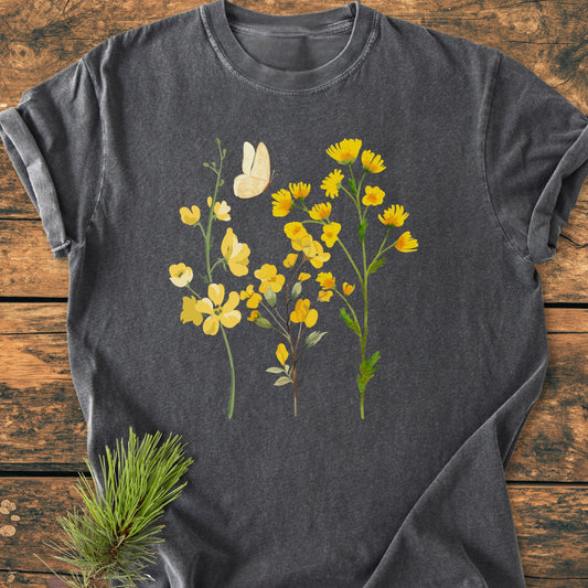 Yellow Boho Flowers - Vintage Heavyweight Tee: A charcoal-gray T-shirt with yellow wildflowers and a butterfly print, displayed on a wooden surface. Made from soft, pre-shrunk ring-spun cotton for comfort and durability.