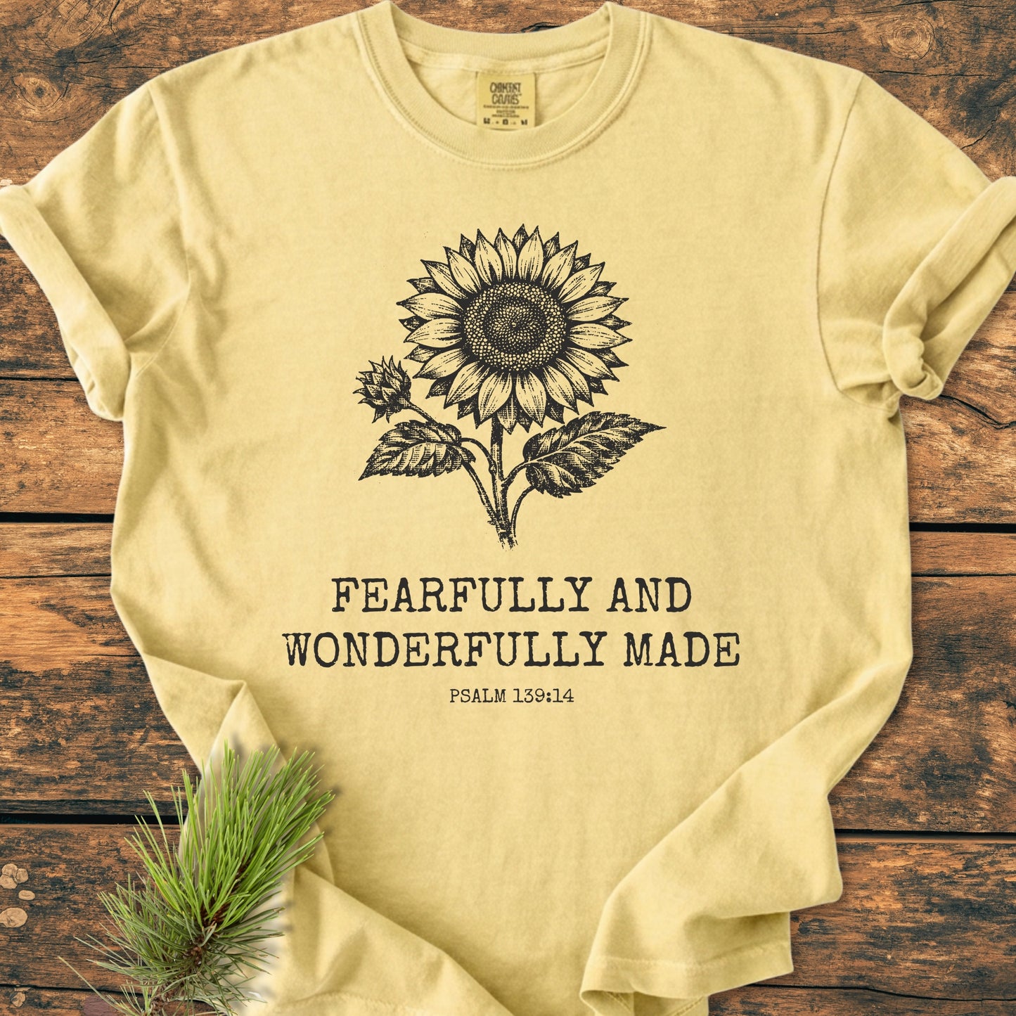 Fearfully And Wonderfully Made, Psalm 139:14 - Vintage Wash Tee featuring a black sunflower drawing and text on a pale-yellow, garment-dyed, soft-washed T-shirt, enhanced by a pine sprig accent.