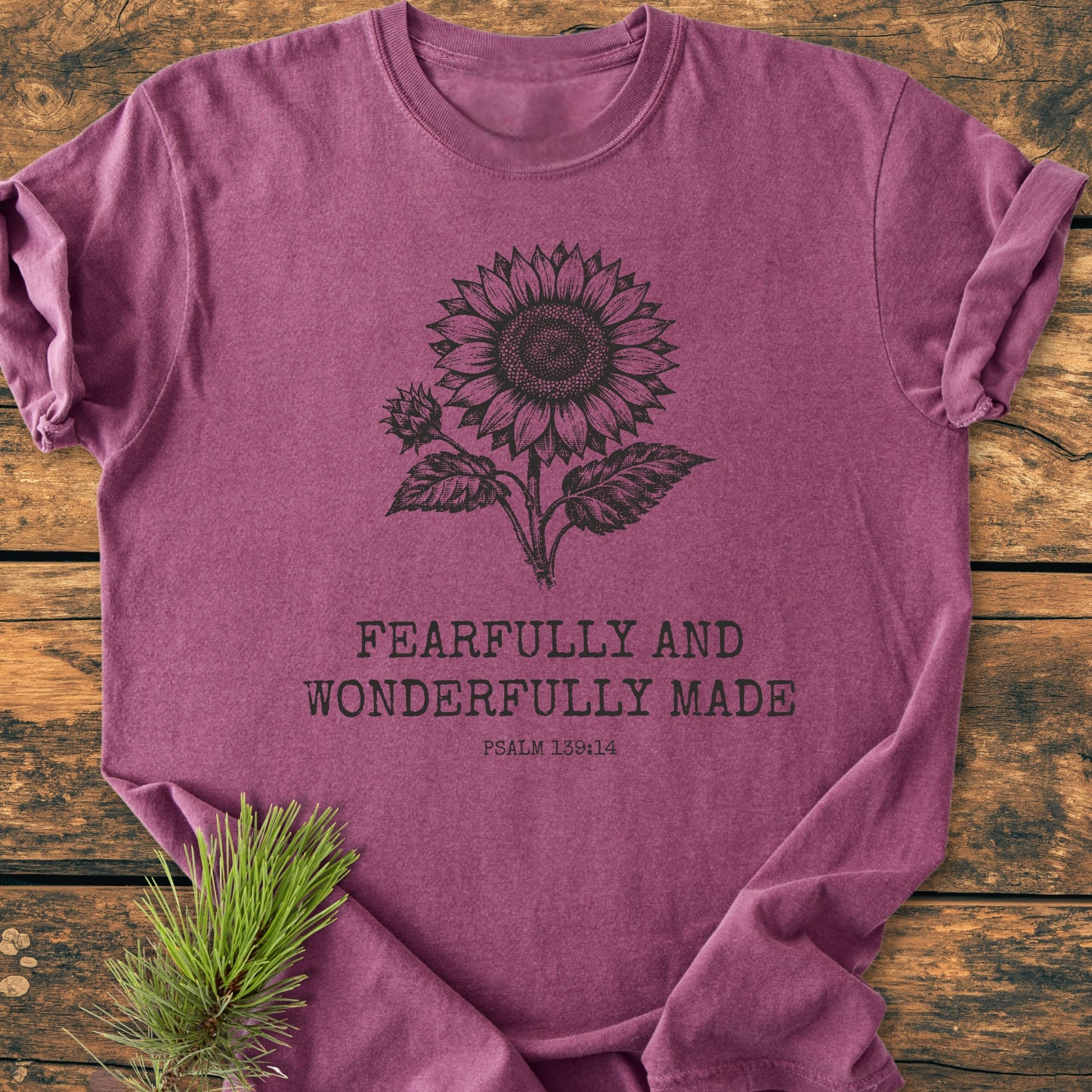 Heather-purple vintage wash tee with hand-drawn sunflower above FEARFULLY AND WONDERFULLY MADE and PSALM 139:14, laid on wood, pine sprig beside. Pre-shrunk, ring-spun cotton, relaxed fit.