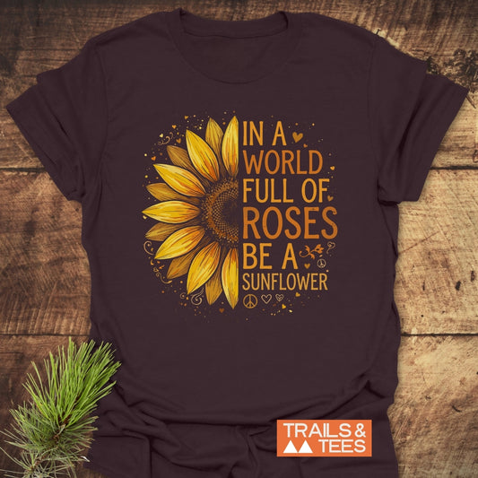 Be A Sunflower T-Shirt featuring a large sunflower graphic with the uplifting quote, surrounded by decorative hearts and peace sign. Overlaid TRAILS & TEES logo on soft, durable cotton.