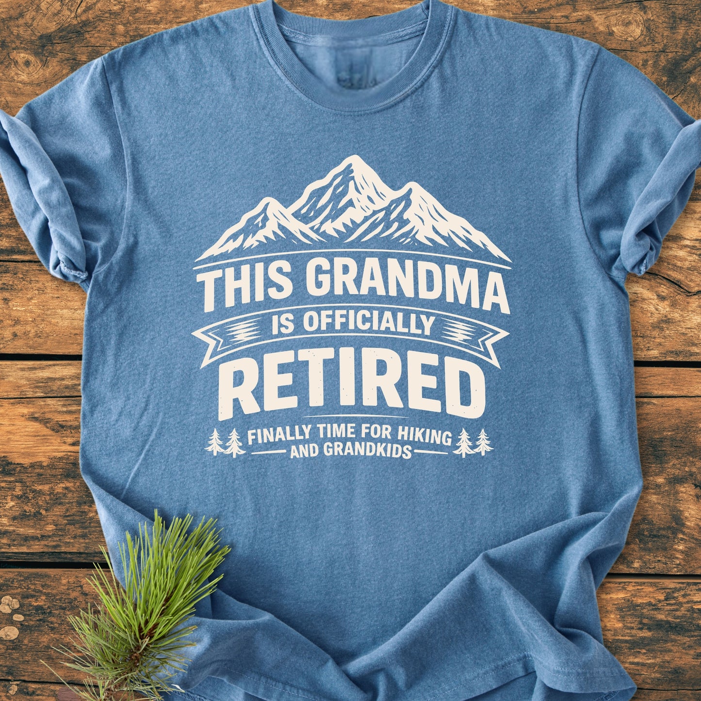 This Grandma is Officially Retired - Vintage Wash Tee, featuring a mountain graphic and retirement text, displayed flat. Made from soft, durable, 100% ring-spun cotton, perfect for comfort and style.