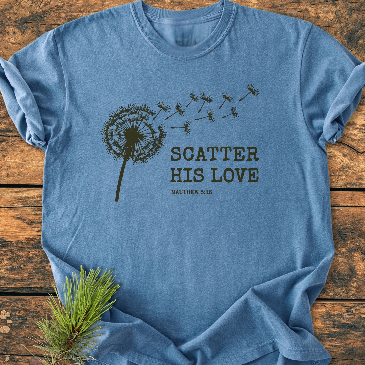 Scatter His Love, Matthew 5:16 - Vintage Wash Tee features a stylized dandelion design with scriptural text, laid flat. The soft, garment-dyed fabric offers a relaxed, durable fit.