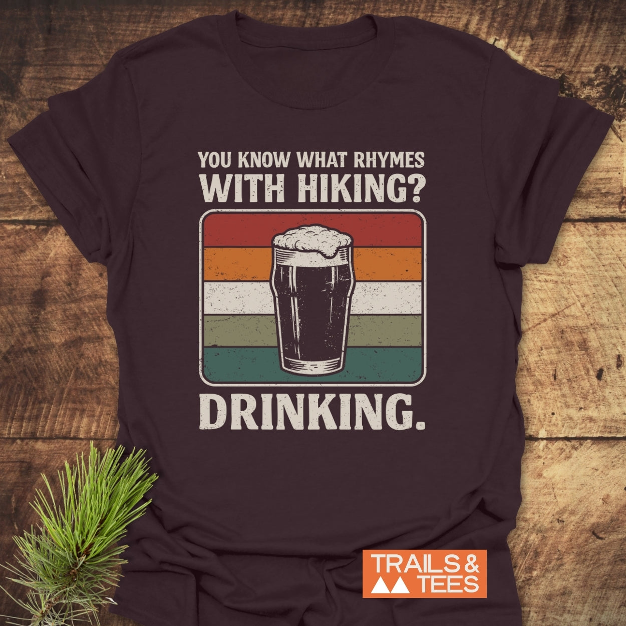 What Rhymes With Hiking? Softstyle T-Shirt features a vintage pint graphic with humorous text, ideal for hikers who enjoy both trails and post-adventure drinks.