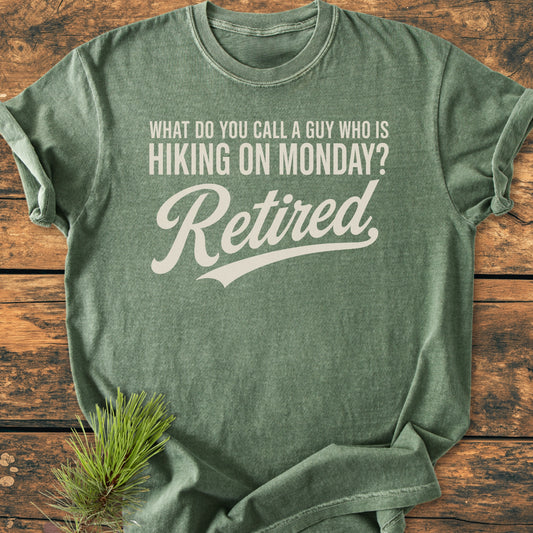 Hiking On Monday - Vintage Wash Tee featuring a humorous slogan laid flat on rustic wood, accented with a pine sprig. Perfect for those embracing leisurely post-retirement trails over workdays.